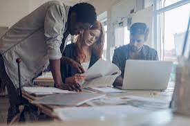 Business professionals collaborating around laptop and documents - demonstrating Next Horizons Consulting's collaborative approach to problem-solving and strategic implementation